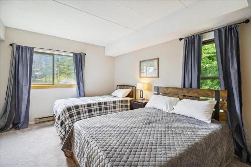 two beds in a room with two windows at Pinnacle D17 in Killington