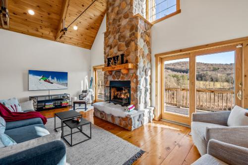 - un salon avec une cheminée en pierre et une grande fenêtre dans l'établissement New & Stunning Chalet! Reno'd, Hot-Tub, Barrel Sauna, Slope Views, Fire Pit, à Ellicottville