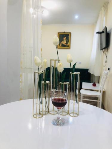 a table with a glass of wine and white flowers at Kutaisi Hotel Bzholebi in Kutaisi