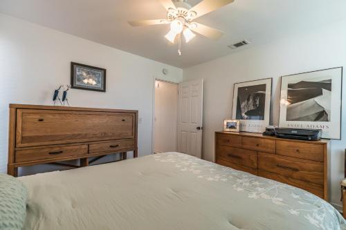 a bedroom with a bed and a dresser and a ceiling fan at Marsh Views - Nautical Watch - Steps to the Pool in Harbor Island