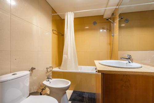 a bathroom with a toilet and a sink and a tub at Akisol Troia Pearl in Troia