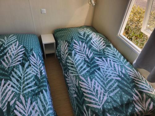 two beds in a small room with blue and green leaves at mobil home v198 in Sigean