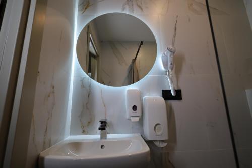 a bathroom with a mirror and a white sink at Luna Self Check-in Hotel Klaipeda in Klaipėda
