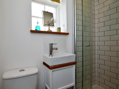 a bathroom with a sink and a toilet and a window at 3 Bed in Folkestone 75607 in Sandgate
