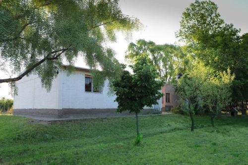 ein kleines weißes Haus in einem Hof mit Bäumen in der Unterkunft Colonia Indalo casa de campo in San Carlos