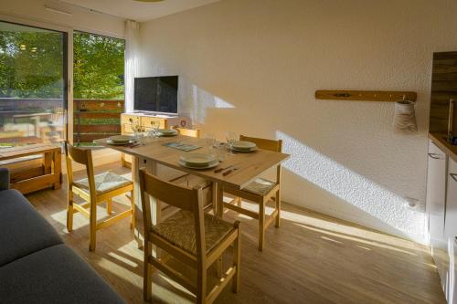 une salle à manger avec une table, des chaises et une télévision dans l'établissement Studio Pastilla - Welkeys, à Huez