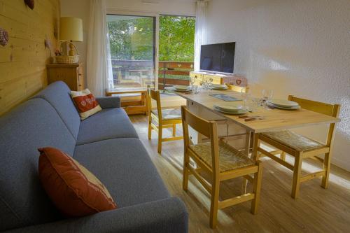 un salon avec une table et un canapé bleu dans l'établissement Studio Pastilla - Welkeys, à Huez
