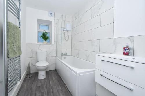 a white bathroom with a toilet and a tub and a sink at Lyndale House - By Sigma Stays in Crewe