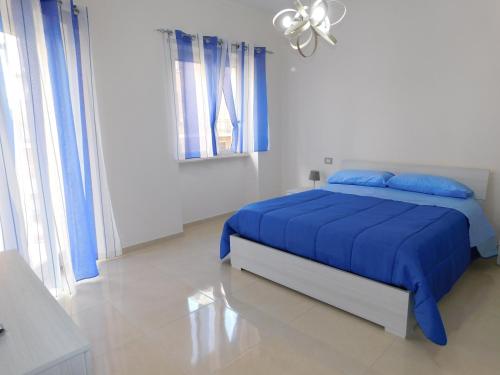 um quarto branco com uma cama azul com lençóis azuis em Cariteo Home em Nápoles