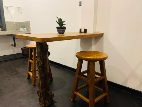 una mesa de madera y 2 taburetes en una habitación en Beacon en Hikkaduwa