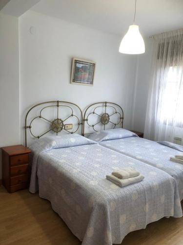 1 dormitorio con 2 camas y toallas. en Apartamentos Villa Maria, en Canales