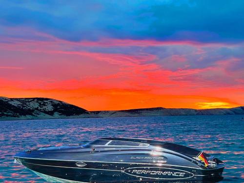 a boat sitting in the water with a sunset at Villa Olivija-direkt am Strand! in Stara Novalja