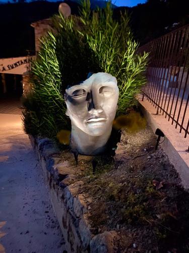 a statue of a face is in a garden at Gîte A Funtana Montestremo, Balagne, Haute Corse in Manso