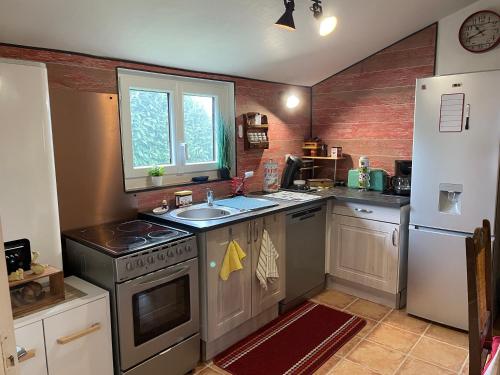 La cuisine est équipée d'un évier, d'une cuisinière et d'un réfrigérateur. dans l'établissement LE PETIT CHALET DE SYLVIANE, à Budelière