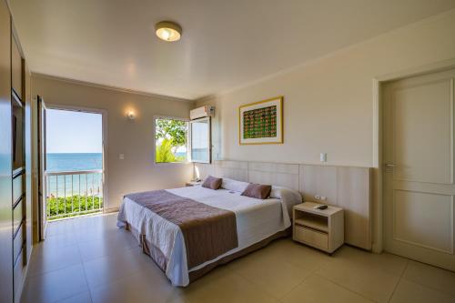 a bedroom with a bed and a view of the ocean at Hotel Vila do Farol in Bombinhas