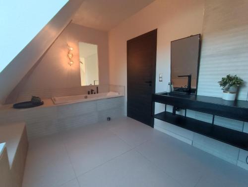 ein Badezimmer mit einer Badewanne, einem Waschbecken und einem Spiegel in der Unterkunft Ame O des Flandres La Villa in Boeschèpe