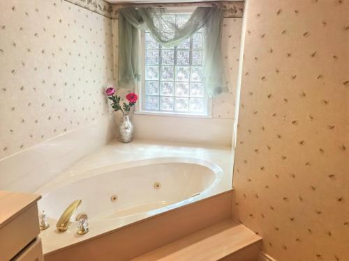 baño con bañera blanca y ventana en Creek side villa, en Surrey