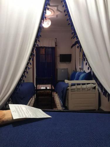 a bedroom with a tent with a bed and a television at Hôtel Riad Gnaoua in Essaouira