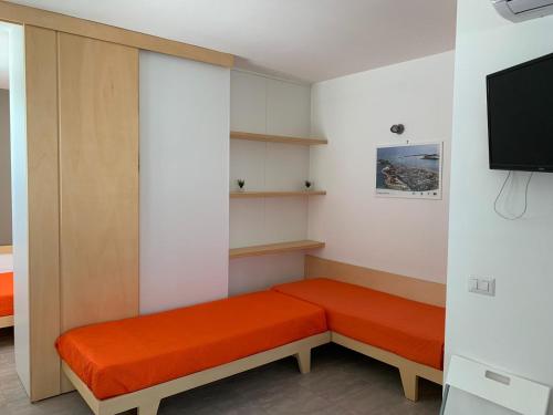una camera con panca con cuscini arancioni e TV di Viva a Porto Cesareo