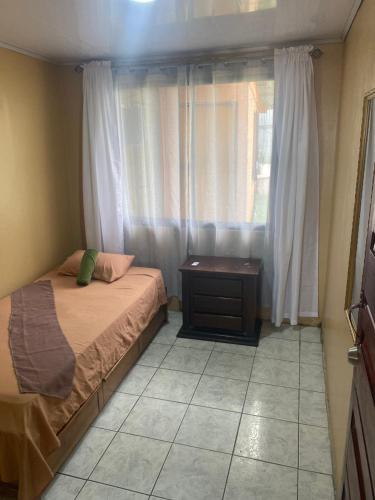 a bedroom with a bed and a dresser and a window at HOSTEL CASA MARINA in Puerto Limón