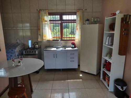 a kitchen with a sink and a table and a refrigerator at Pousada da Lua in Rolante