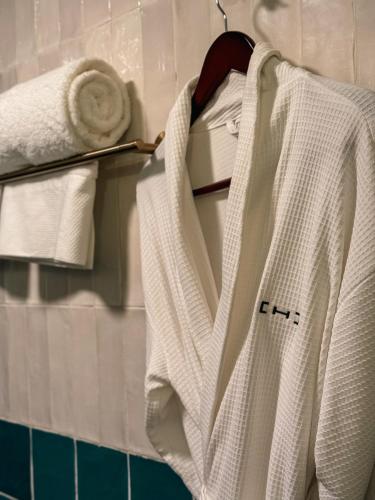 a white robe is hanging on a rack in a bathroom at Casa H Hotel Boutique in San Luis Potosí