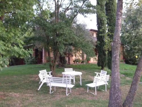 un groupe de bancs et de tables blancs dans une cour dans l'établissement Villa Mimosa, à Medesano