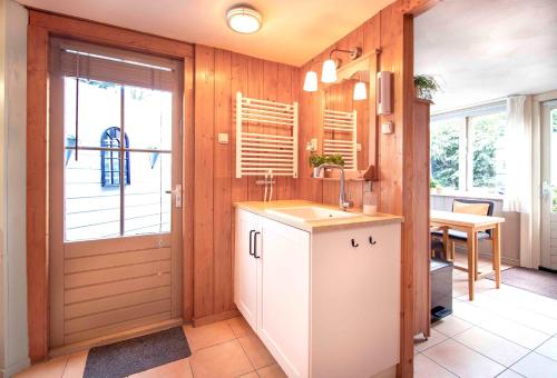 een keuken met een wastafel, een deur en een tafel bij B&B Noordzee-kerstdeco-Sauna-Strand7km-Kennemerduinen in Driehuis