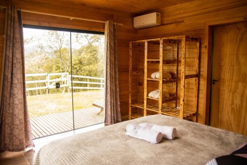 ein Schlafzimmer mit einem Bett und einem großen Fenster in der Unterkunft Cabana na Serra Catarinense in Bom Retiro