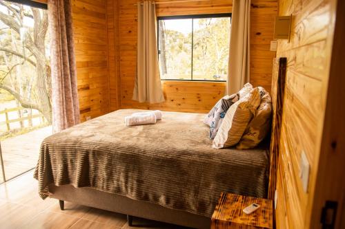 Bett in einem Holzzimmer mit Fenster in der Unterkunft Cabana na Serra Catarinense in Bom Retiro
