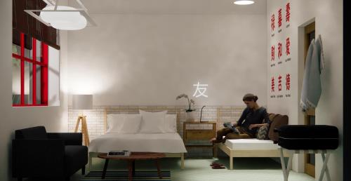 a man sitting on a couch in a room with a bed at Yu Cafe Hostel in Songkhla