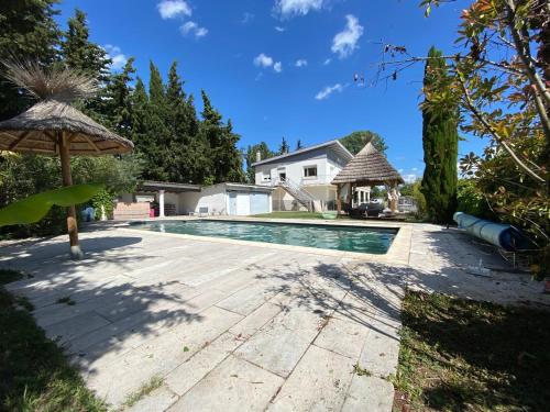 - une piscine avec un parasol et une maison dans l'établissement Villa les Portes de Provence, à Sauzet
