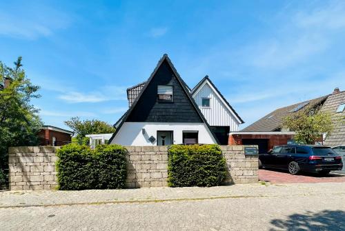 uma casa a preto e branco com uma parede de pedra em Ferienhaus Liese em Carolinensiel