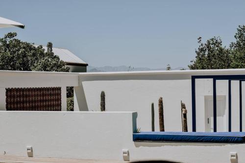 a bench on the side of a white wall at Dodo House in Riebeek-Kasteel