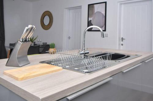 a kitchen sink with a dish drying rack on a counter at Lyndale Lofts - By Sigma Stays in Crewe