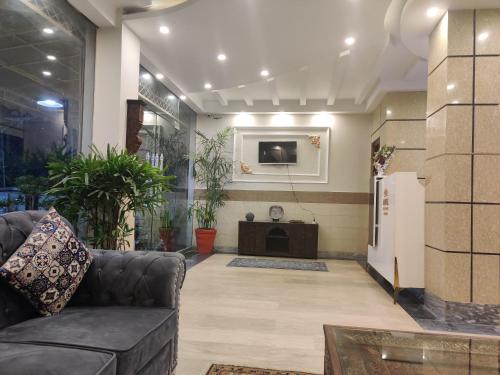 uma sala de estar com um sofá e uma televisão em Hotel Swiss Pearl em Lahore