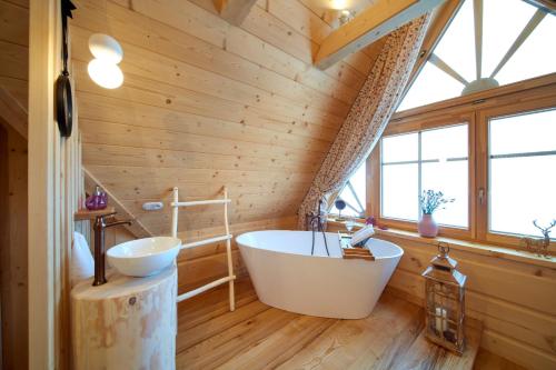a bathroom with a large tub in a wooden wall at Marusina Chalets in Szaflary