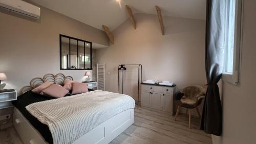 a bedroom with a bed with pink pillows on it at Gîte 4/6 personnes La mélodie du bonheur in Habas