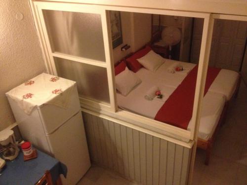 a small bedroom with a bed and a refrigerator at Alkyonis Apartments in Panormos Kalymnos