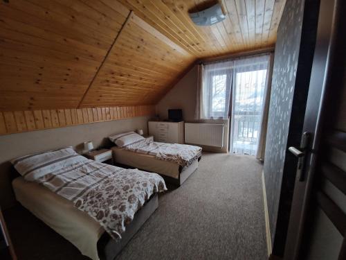 two beds in a bedroom with a wooden ceiling at Arkadia in Muszyna