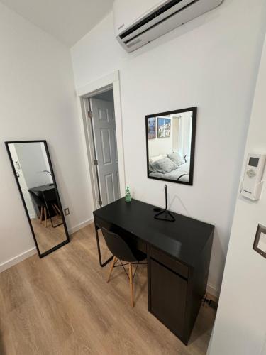 Escritorio negro en una habitación blanca con espejo en Santoniri private room en Seattle