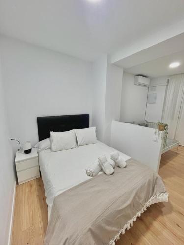 a white bedroom with a bed with two towels on it at Lofts 4Towers - La Paz in Madrid