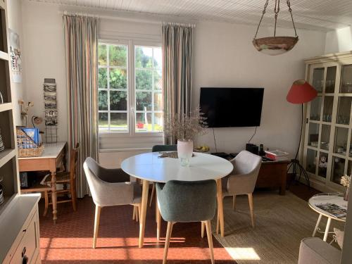 un salon avec une table et des chaises blanches dans l'établissement LA PETITE PRAIRIE 400m de la plage, à Jard-sur-Mer