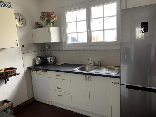 eine Küche mit weißen Schränken und einer Spüle und einem Fenster in der Unterkunft LA PETITE PRAIRIE 400m de la plage in Jard-sur-Mer