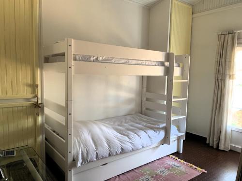ein weißes Etagenbett in einem Zimmer mit Fenster in der Unterkunft LA PETITE PRAIRIE 400m de la plage in Jard-sur-Mer