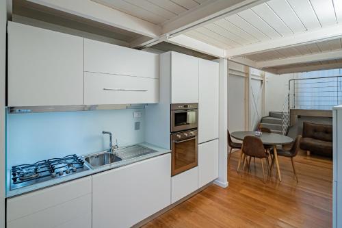 a kitchen with white cabinets and a table in a room at Anfihouse - Assisi Relais in Assisi