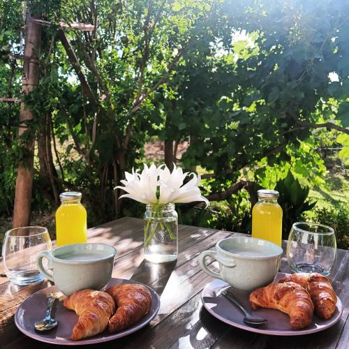 a wooden table with croissants and cups and drinks at Entre racimos, glamping entre viñedos in Ciudad Lujan de Cuyo
