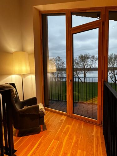 une chambre avec des portes coulissantes en verre donnant sur l'eau dans l'établissement Idille2, à Ikšķile