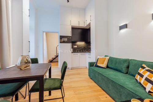 a living room with a green couch and a table at Elegant Stay Near Hungarian Museum by Pink Flamingo in Budapest