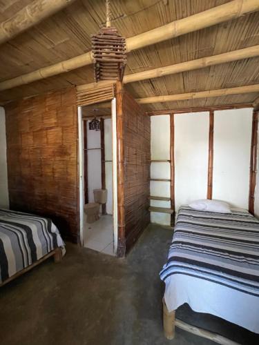 a bedroom with two beds in a room with wooden walls at Naif habitaciones in Máncora